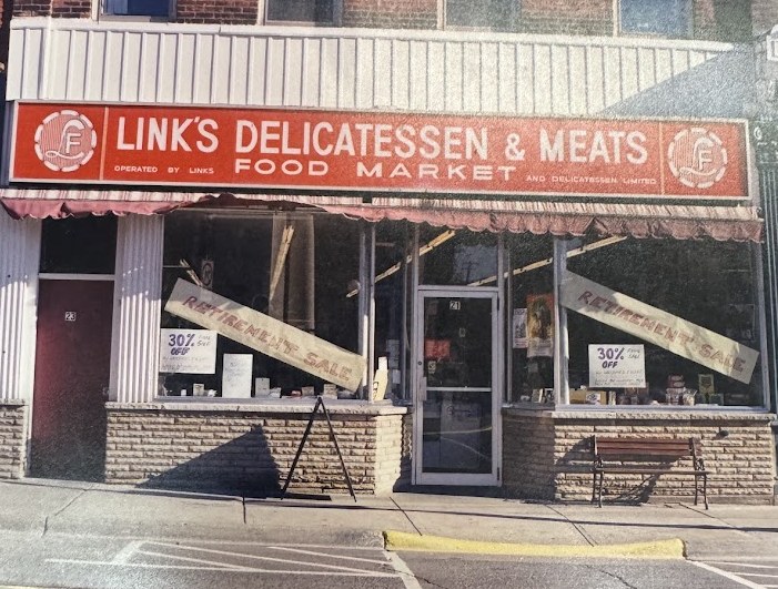 21 King St W in Dundas as Link's Delicatessen and Meats, a red shop sign above two display windows with retirement sale signs taped across them